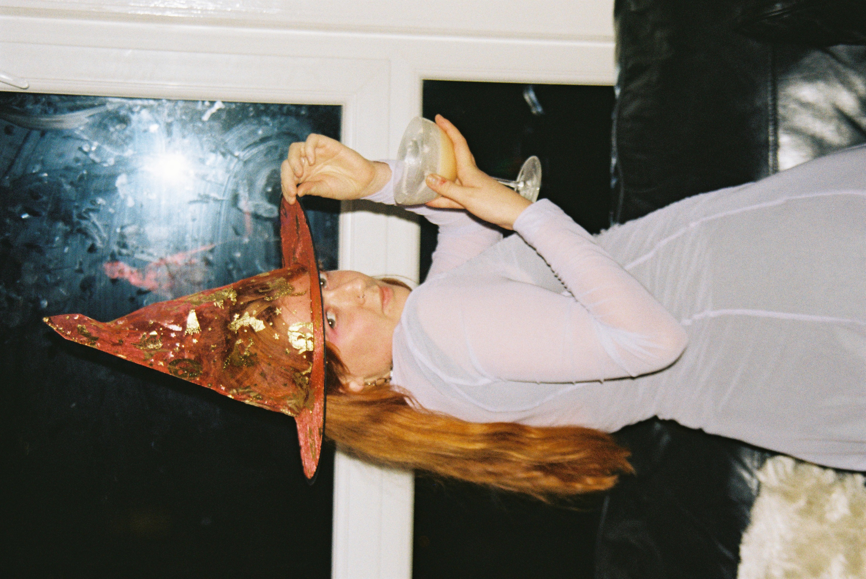 Miriam posing with drink and an orange witch hat