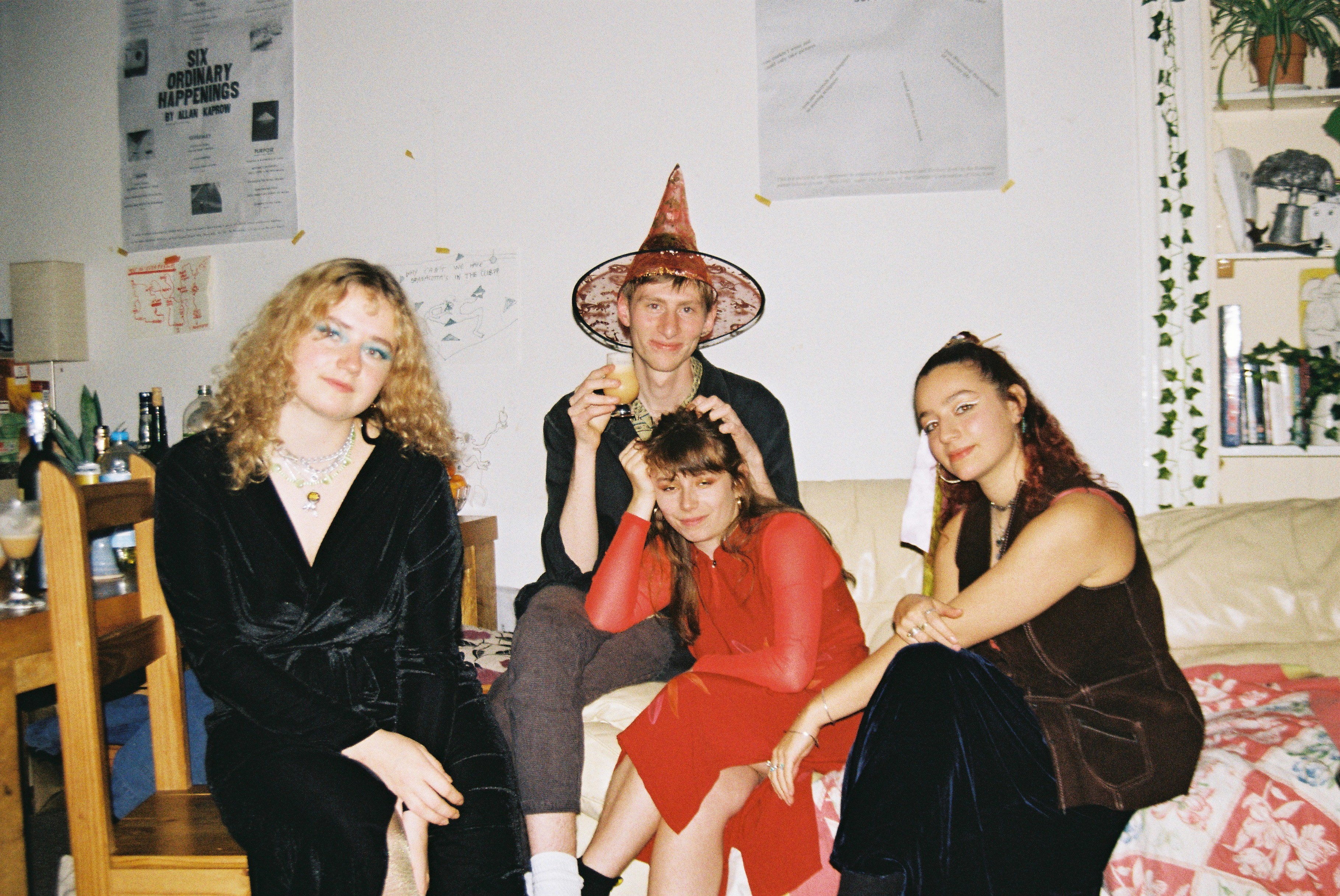 Maria is sitting on a chair next to Gabriel who is wearing an orange with hat and Maxime and Gemma