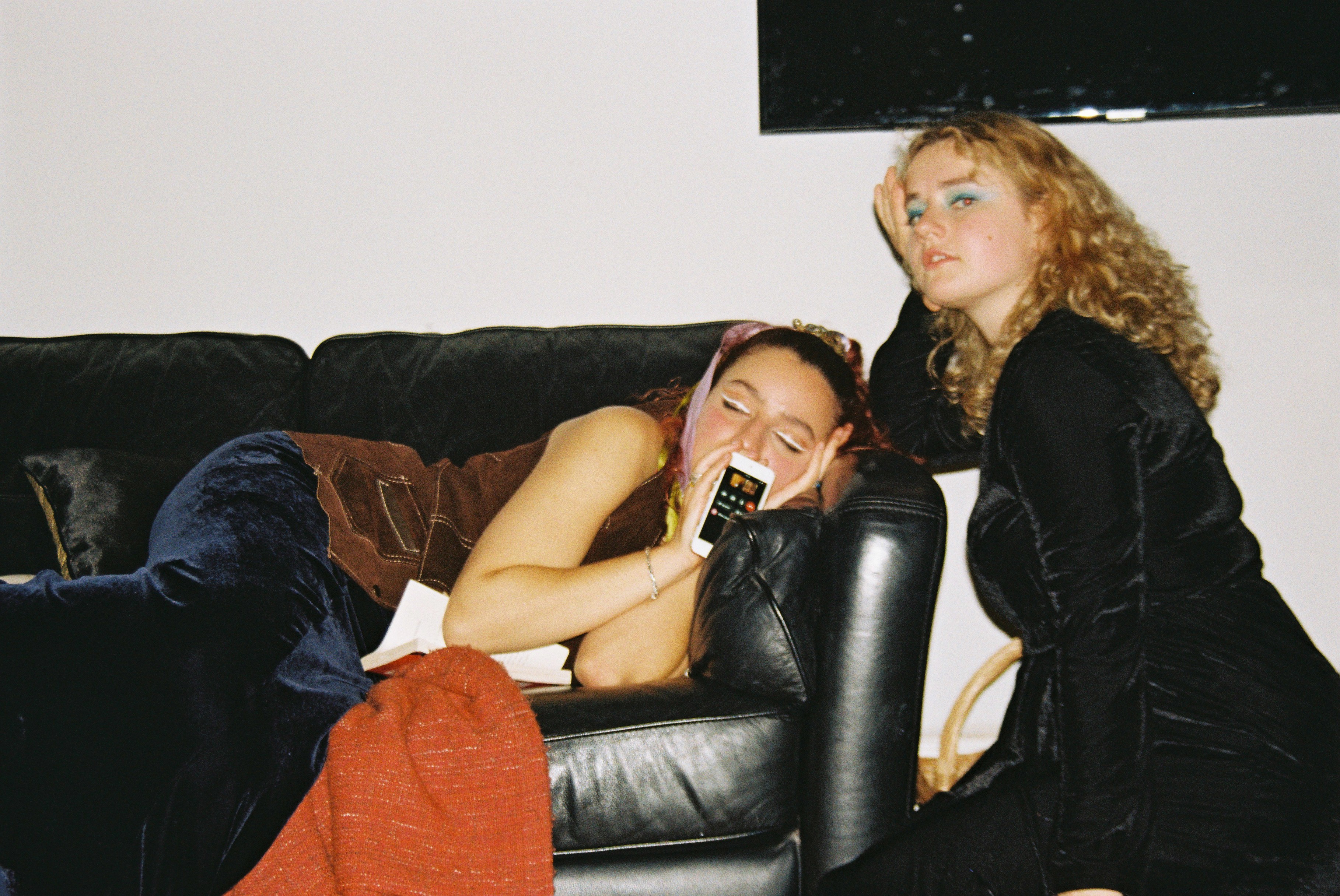 Gemma asleep on a couch showing the screen of a phone on facetime with Maria posing next to the couch.