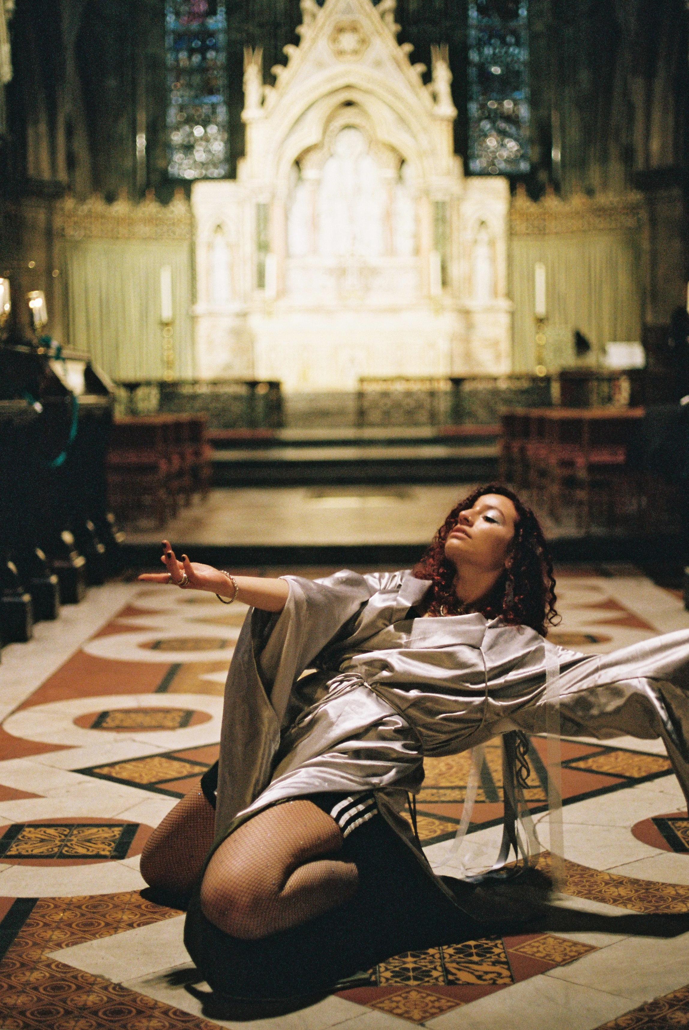 alliyah kneels on the ground of the cathedral dancing
