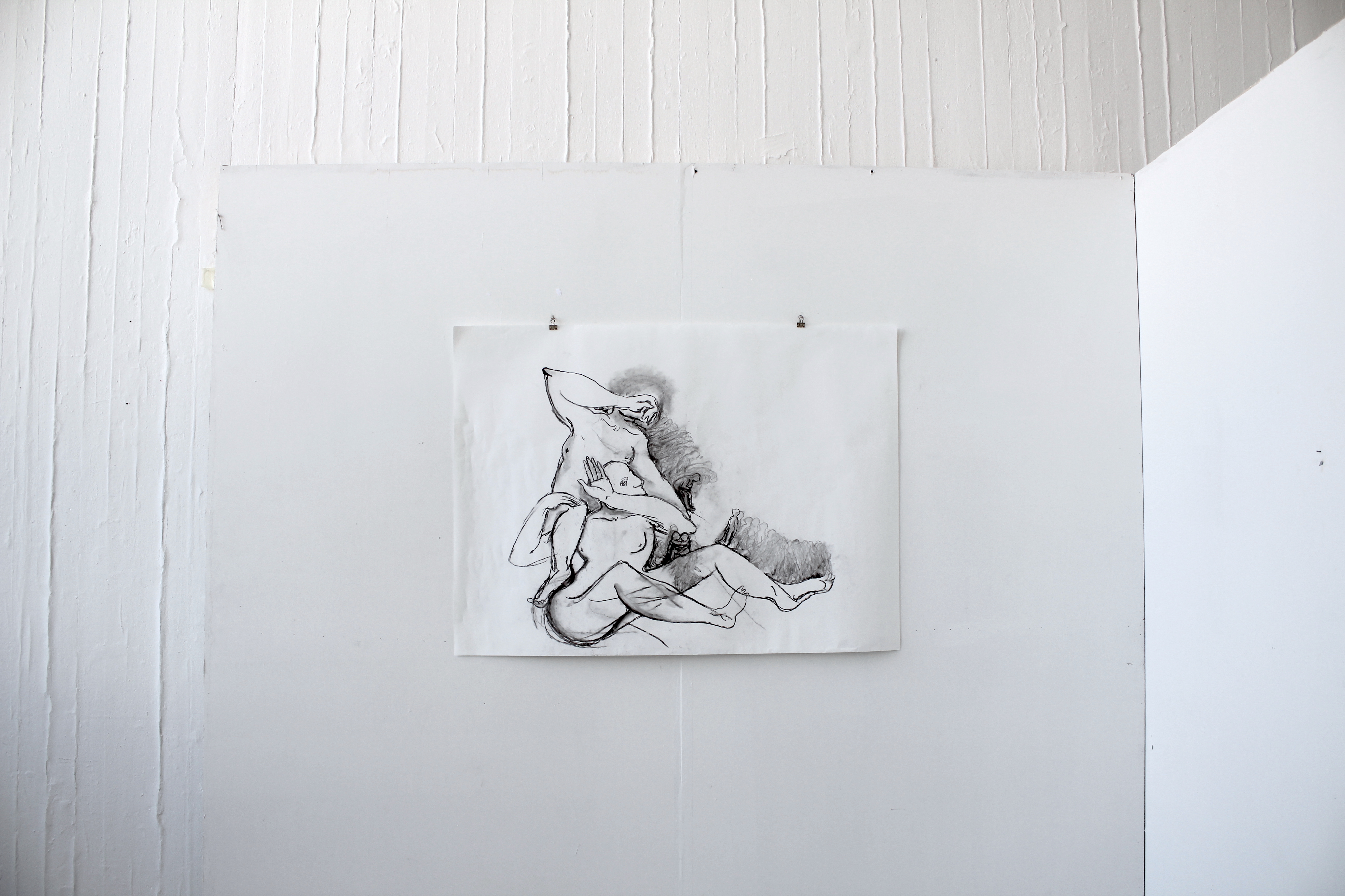 Large drawing of the two figures with tiny charactes walking on them, installed on a white wall
